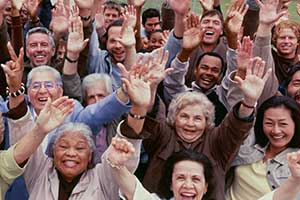 Large group of people smiling with their hands in the air.